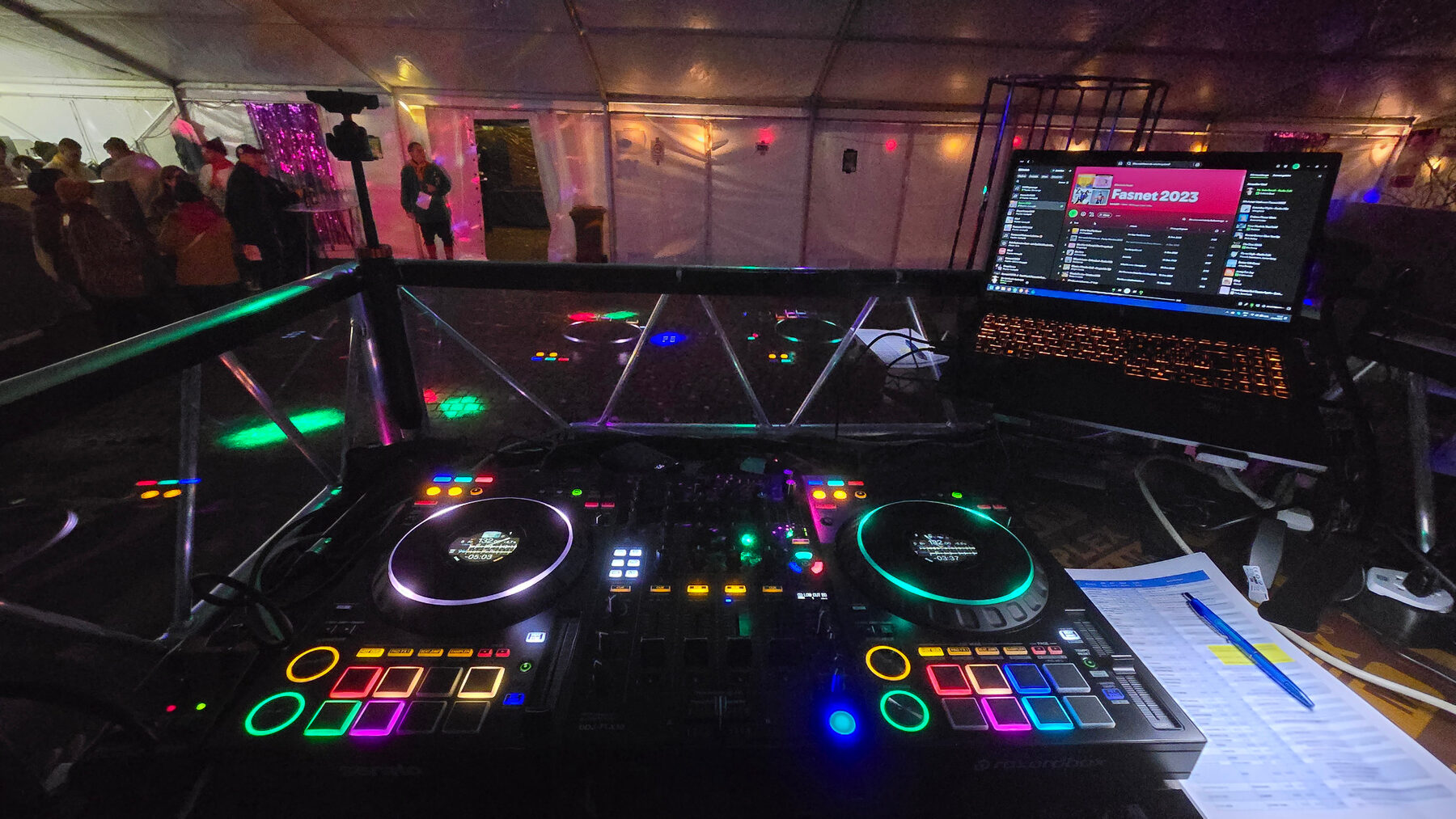 Beleuchteter DJ-Controller und Laptop am DJ-Pult