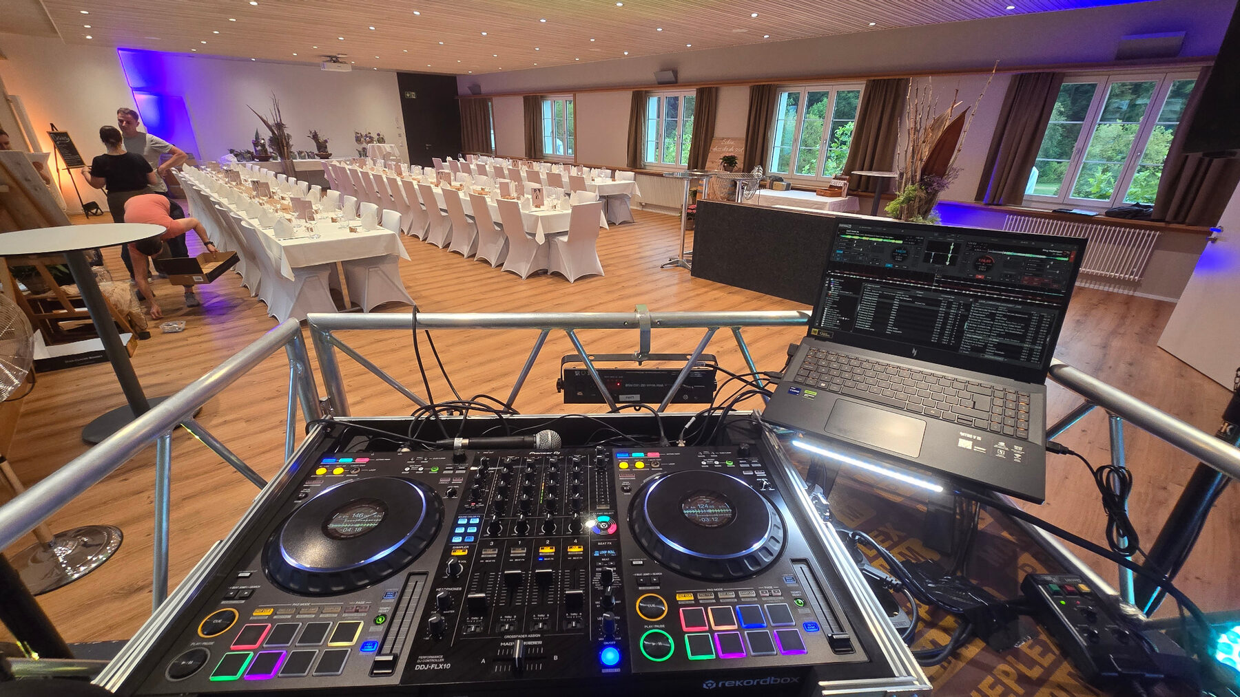 DJ-Pult mit Blick auf einen festlich gedeckten Hochzeitssaal